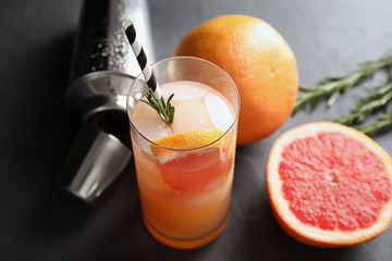 Composition with glass of grapefruit cocktail on dark table