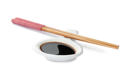 Dish of soy sauce with chopsticks on white background