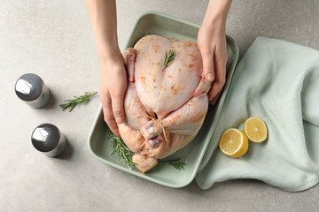 Woman preparing whole turkey at table, top view