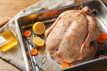 Baking dish with raw spiced turkey on table