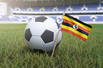 Naklejka premium Ugandan flag in stadium field with soccer football