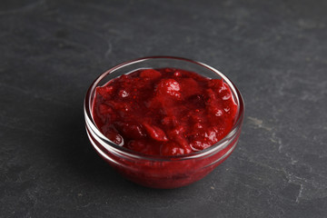 Bowl of cranberry sauce on grey background, closeup