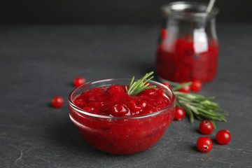 Bowl of cranberry sauce with rosemary on grey table, closeup