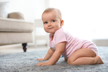 Cute baby girl sitting on floor in room