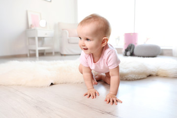 Cute baby girl crawling on floor in room