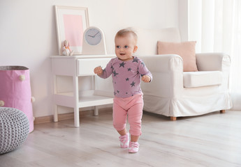 Cute baby girl walking in room at home