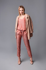 Young stylish woman in trendy shoes on grey background