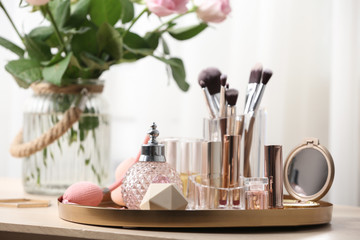 Tray with different makeup products and accessories on dressing table