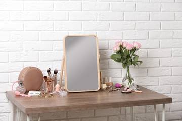 Dressing table with different makeup products and accessories in room interior