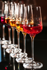 Row of glasses with different wines on table against blurred background