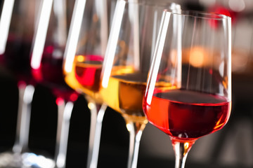 Row of glasses with different wines on blurred background, closeup