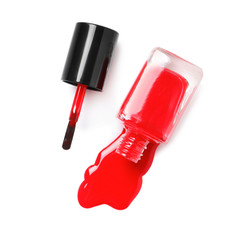 Spilled color nail polish with bottle and brush on white background, top view