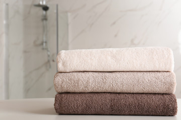 Stack of clean towels on table in bathroom. Space for text