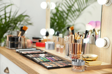 Set of luxury makeup products and accessories on dressing table with mirror. Space for text
