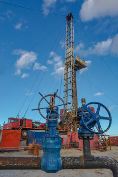 The design of the drilling rig for deep drilling in oil and gas against a blue sky. Many drill pipes installed vertically.