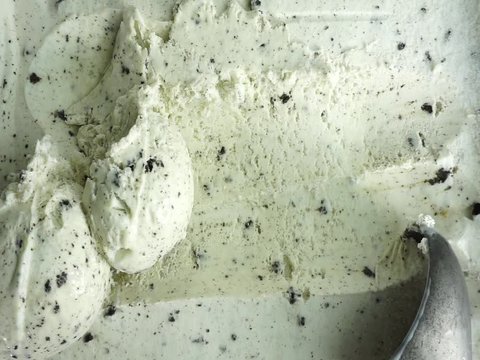 Slow motion of scooping vanilla ice cream with spoon.