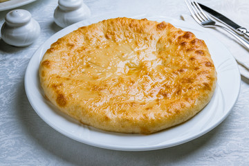 Ossetian pie with cheese on white plate