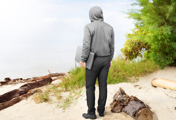 Rear view of man in black hoodie carrying laptop in his hand