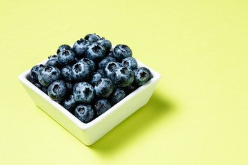 Fresh blueberries inside pot on green background.
