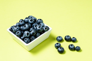 Fresh blueberries inside pot on green background.