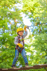Beautiful little child climbing and having fun in adventure Park. Hiking in the rope park girl in...