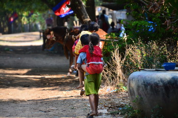 カンボジアのクラチェ　メコン川沿いの村　大きな子供が小さな子供をおんぶする姿　路上に佇む馬