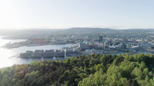 4K aerial of the Oslo city line with a backdrop of downtown Oslo and Bjoervika, a popular tourist attraction with the Munch museum, Barcode and Soerenga pier, in evening with forward motion.