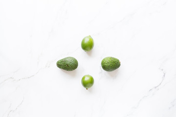 Fresh avocado and lime lying on a white marble background. Flat lay, top view with copy space.