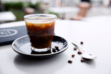 Freshly poured hot black coffee in glass at cafe table