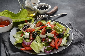 Greek salad with fresh cucumber, cherry tomatoes, sweet pepper, lettuce,red onion, olives and olive oil and feta cheese. Healthy food concept