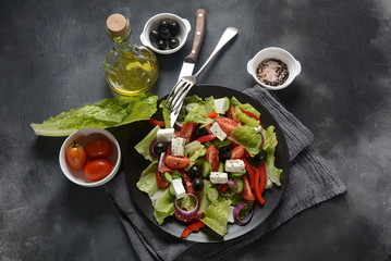 Greek salad with fresh cucumber, cherry tomatoes, sweet pepper, lettuce,red onion, olives and olive oil and feta cheese. Healthy food concept