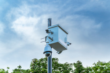 CCTV security camera, trees and blue sky.