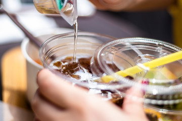コーヒーにシロップを注ぐ手