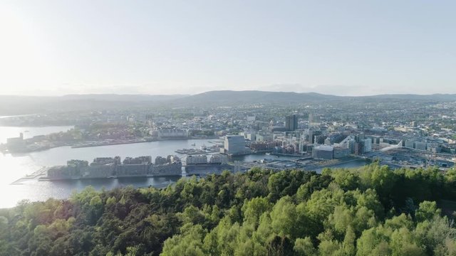 4K aerial of the Oslo city line with a backdrop of downtown Oslo and Bjoervika, a popular tourist attraction with the Munch museum, Barcode and Soerenga pier, in evening with left pan motion.