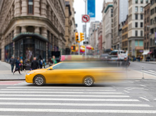 Motion blur of yellow taxi cab speeding through an intersection on 23rd Street in Midtown Manhattan New York City