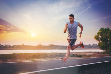 Silhouette of man running sprinting on road. Fit male fitness runner during outdoor workout with...