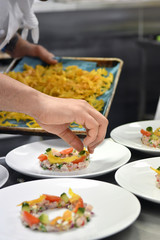 close up of a hand decorating entree on the bench in a professional kitchen