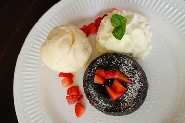 chocolate lava cake set with ice cream and strawberry on white plate