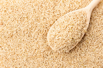 Brown rice background with spoon.