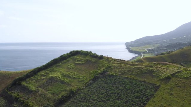 A drone reveal shot of boulder beach from the rolling hills of Batanes.