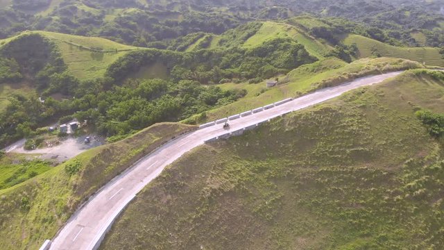 A drone shot following a man riding a scooter near the boulder beach of Batanes.