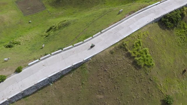 A spotlight drone shot of a man riding a scooter in Batanes.