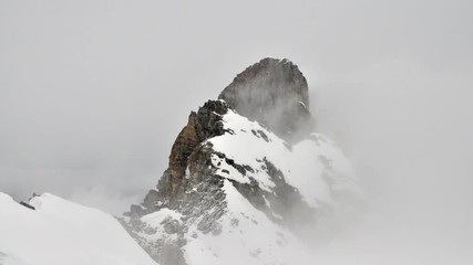 time lapse of cloud rolling around a snow covered mountain peak in the french alps in winter - Powered by Adobe