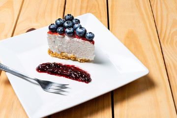 Piece of freshness delicious blueberry cheese cake in white plate is sweet baked bakery dessert on wooden table.