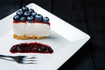 Piece of freshness delicious blueberry cheese cake in white plate is sweet baked bakery dessert on wooden table.