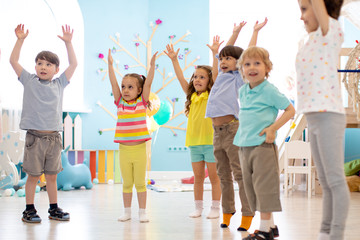 Group of children doing kids gymnastics in kindergarten or daycare