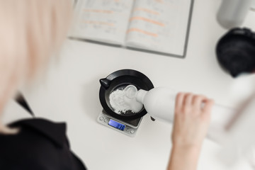 Closeup of hairdresser weighing proportion of hair dye on electronic scales