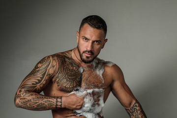 The best bubble foam cleanser for male skin. Strong latino man with soap bubbles on muscular torso. Fit hispanic man with foam bubbles on athletic chest. Enjoying bubble bath