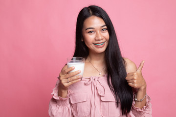 Healthy Asian woman drinking a glass of milk thumbs up.