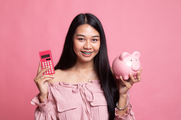 Asian woman with calculator and piggy bank.